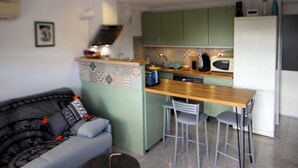 Una cocina compacta con una isla central, taburetes de bar, horno empotrado y refrigerador.