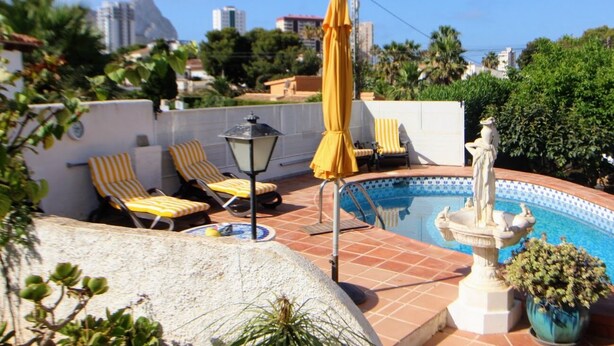 Un área de piscina en la azotea con sillones de descanso, una fuente y vistas de la ciudad.