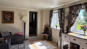 Habitació amb sofà, llum, taula petita, armari i finestra amb cortines.