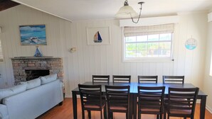 Ein Essbereich mit Holztisch und -stühlen, einem Kamin und einem Fenster mit Jalousien.
