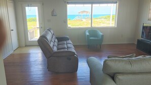 Ein Wohnzimmer mit Holzboden, grauem Sofa, blauem Sessel und Fernseher.