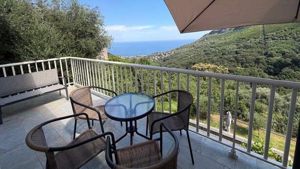 A balcony with wicker chairs and a glass table, overlooking a mountainous landscape and the sea. - Charming apartment in the hills above Erbalunga (Brando)