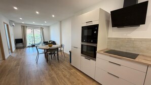 A modern kitchen with a dining area, wooden flooring, and a TV mounted on the wall. - Charming apartment in the hills above Erbalunga (Brando)