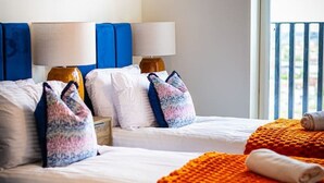 Ein Hotelzimmer mit zwei Betten, einem großen Fenster und einem farbenfrohen abstrakten Gemälde an der Wand.