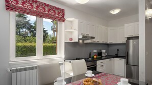 Eine moderne Küche mit weißen Schränken, einem Edelstahl-Kühlschrank und einem Esstisch mit einer rosa Tischdecke.