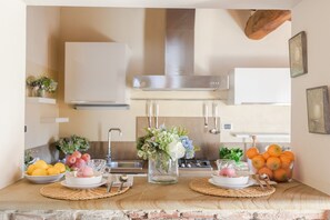 A kitchen counter with a sink, a stove, and a vase with flowers. There are bowls with fruits and a glass pitcher. - Elegant And Refined 2-Bedrooms Apartment In The Heart Of Lucca (Lucca)