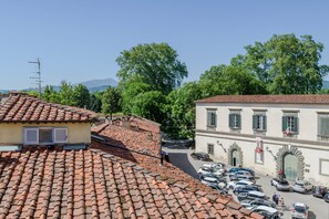 A building with a tiled roof, a parking lot, and trees in the background. - Elegant And Refined 2-Bedrooms Apartment In The Heart Of Lucca (Lucca)