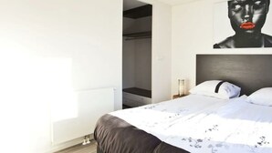 Un dormitorio con una cama, un armario y un cuadro en la pared.