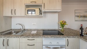 Cocina con encimeras de granito, electrodomésticos de acero inoxidable, armarios de madera y microondas empotrado.
