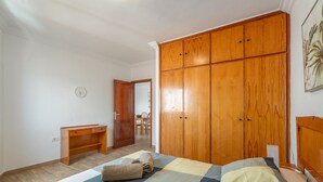 Un dormitorio con cama, armario de madera, escritorio y silla.