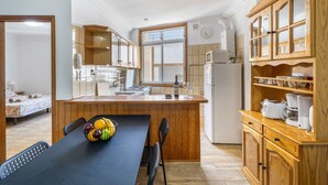 Una cocina compacta con armarios de madera, un comedor con una mesa dispuesta para dos personas y un refrigerador a la vista.
