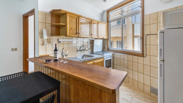 Una cocina con armarios de madera, estufa a gas, refrigerador y ventana con vistas.