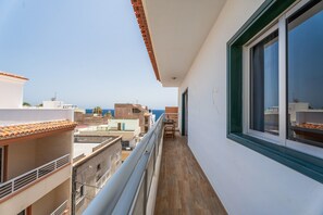 Ein schmaler Balkon mit Blick auf das Meer und andere Gebäude.