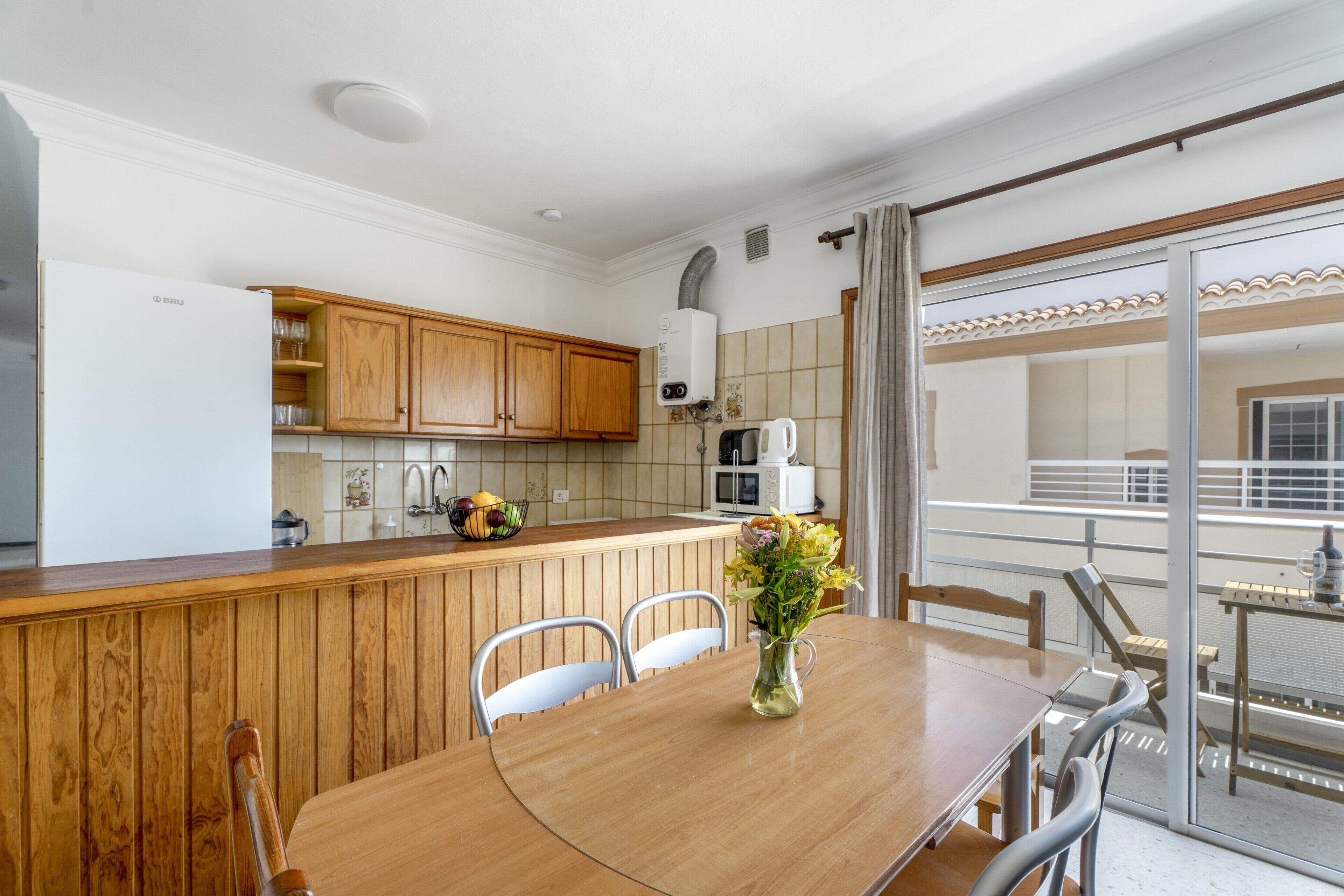 Une cuisine dotée de meubles en bois, d’un îlot central et d’un coin repas avec une table et des chaises.
