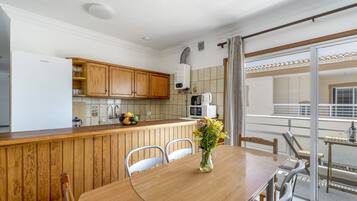 Une cuisine dotée de meubles en bois, d’un îlot central et d’un coin repas avec une table et des chaises.