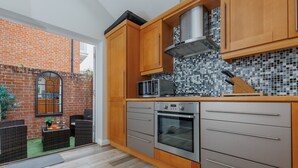 Cozinha moderna com armários de madeira, forno de aço inoxidável e micro-ondas.