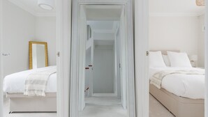 Quarto de hotel com uma cama, mesa de cabeceira, espelho e porta que dá para outro aposento.
