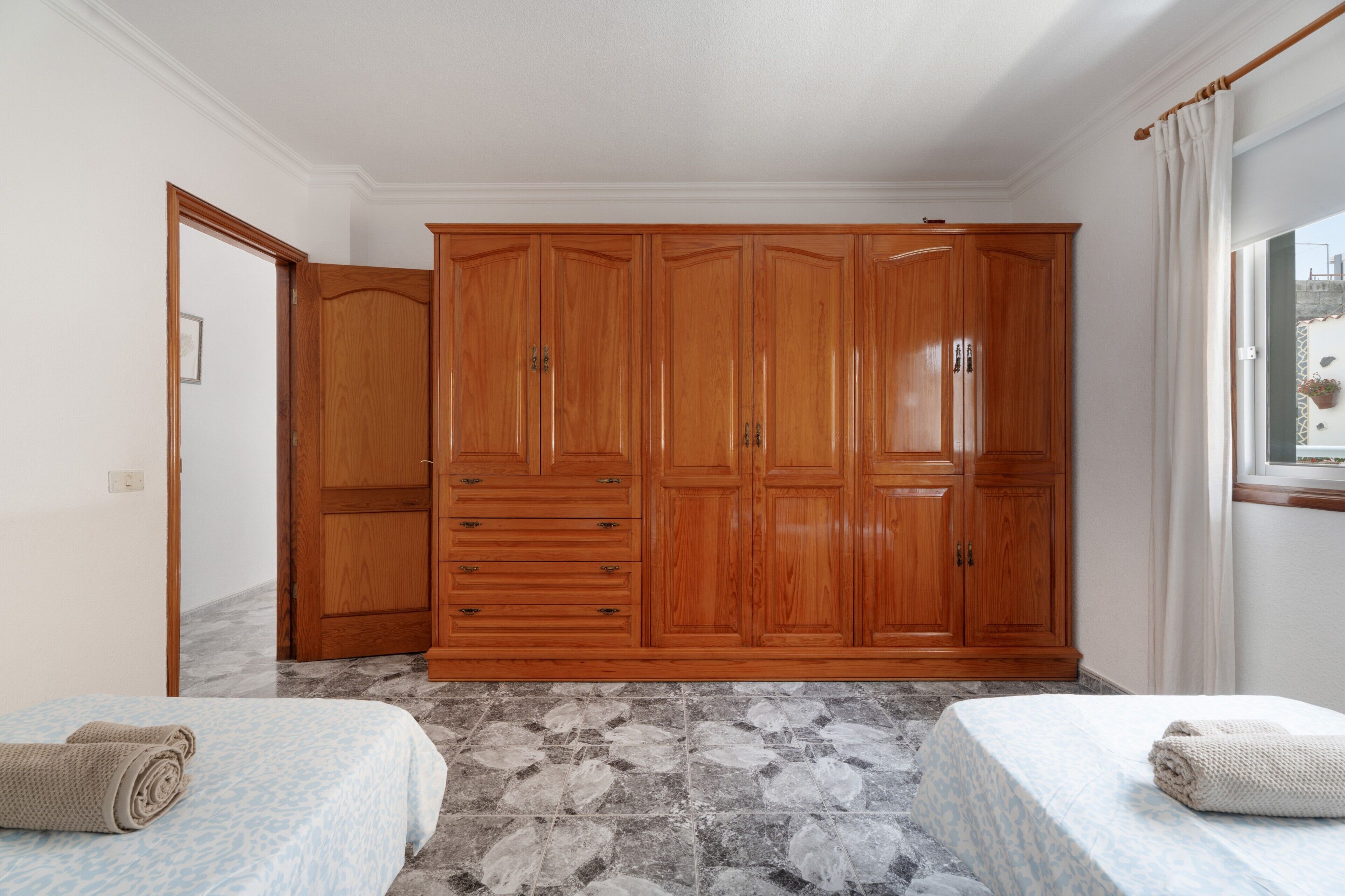 Un dormitorio con un armario grande, dos camas con toallas y una ventana con cortinas.