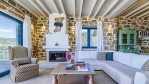 Ein Wohnzimmer mit einer Steinwand, einem weißen Sofa, einem gemusterten Sessel, einem Couchtisch und einem grünen Schrank.