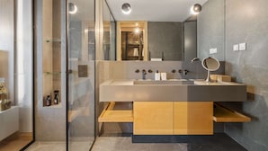 Une salle de bain moderne avec un grand miroir, un lavabo et un espace douche.