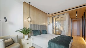 Une chambre moderne avec un grand lit, des tables de chevet, une lampe et une plante.