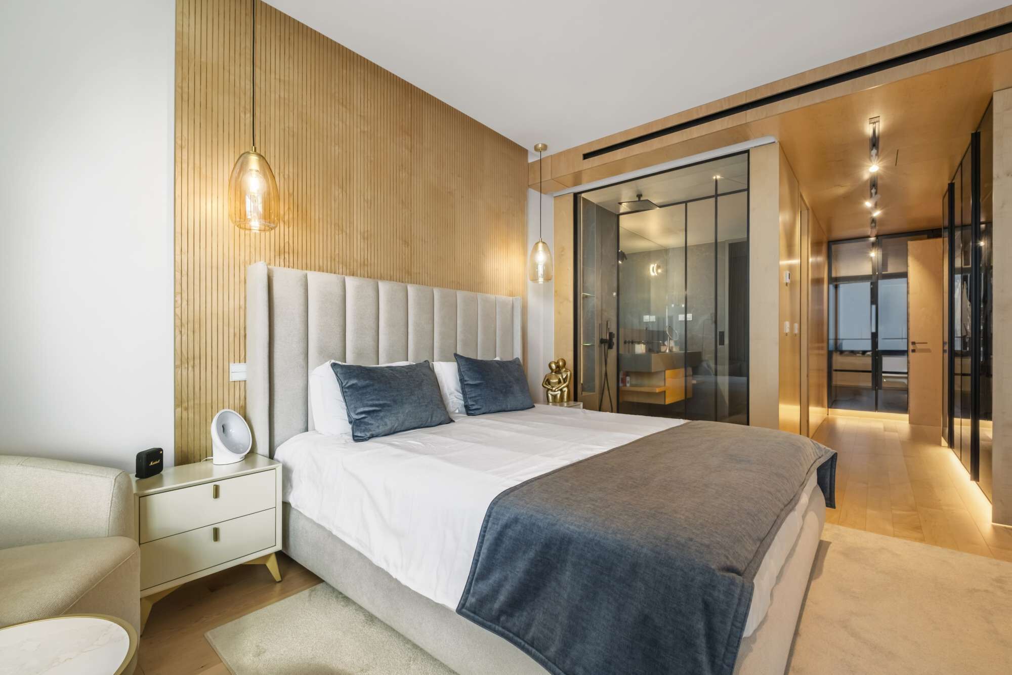 A modern bedroom with a large bed, bedside tables, and a walk-in closet.