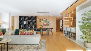Un salon moderne comprenant un canapé, une table à manger et des chaises, une étagère noire décorative et un plancher en bois.