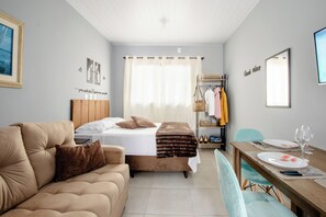 Ein Schlafzimmer mit Bett, einer Couch, einem Esstisch gedeckt mit Tellern und Gläsern sowie einem Spiegel an der Wand.