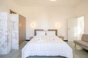Ein Hotelzimmer mit einem großen Bett, zwei Nachttischen, einem Kleiderschrank und einem Sofa.