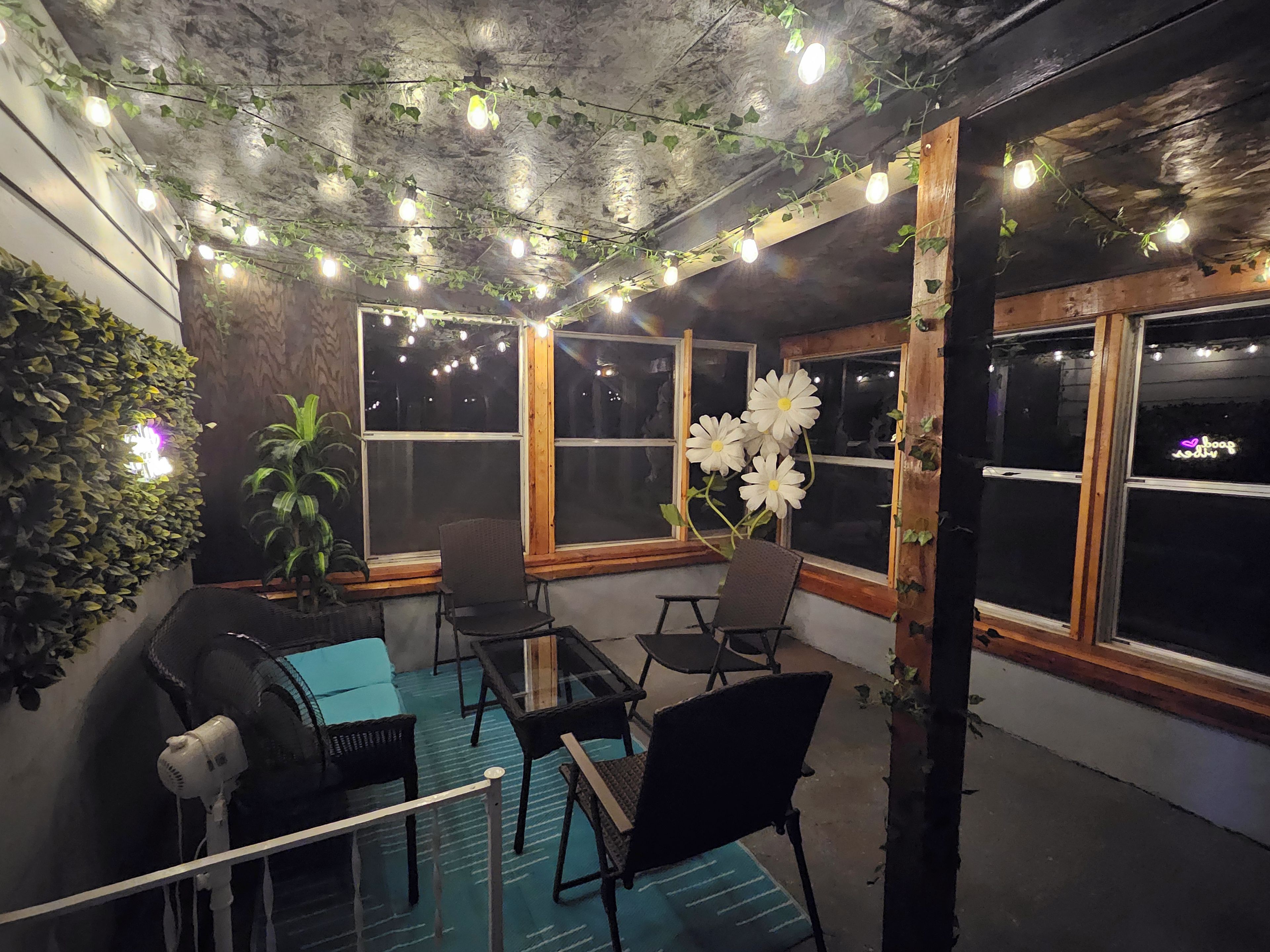 Un espacio interior acogedor con mesas y sillas, ventanas amplias y plantas decorativas.