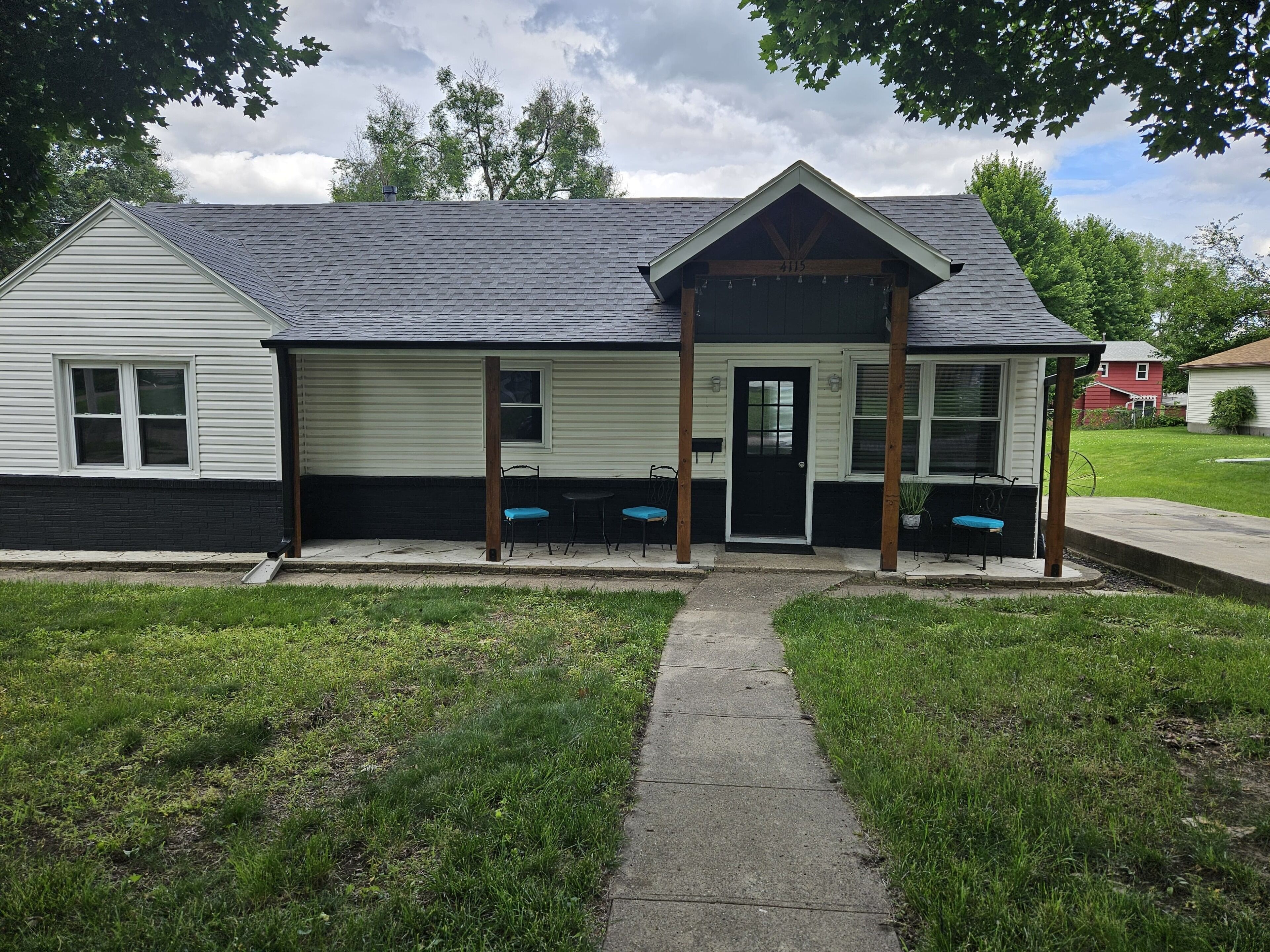 A single-story building with a porch, a black door, and a number '415' on the front.