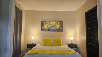 Een slaapkamer met een bed, twee bedlampen, een schilderij aan de muur en een raam met gordijnen.