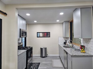 A modern kitchen with grey cabinets, stainless steel appliances, and a tiled backsplash. - Awesome 3-bedroom house with AC in delightful Des Moines (Des Moines)