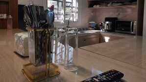 A modern kitchen with a wooden countertop, a glass utensil holder, a remote control, and a window with a view of trees.