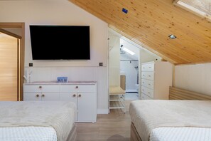 Een slaapkamer met twee bedden, een televisie en een houten plafond.