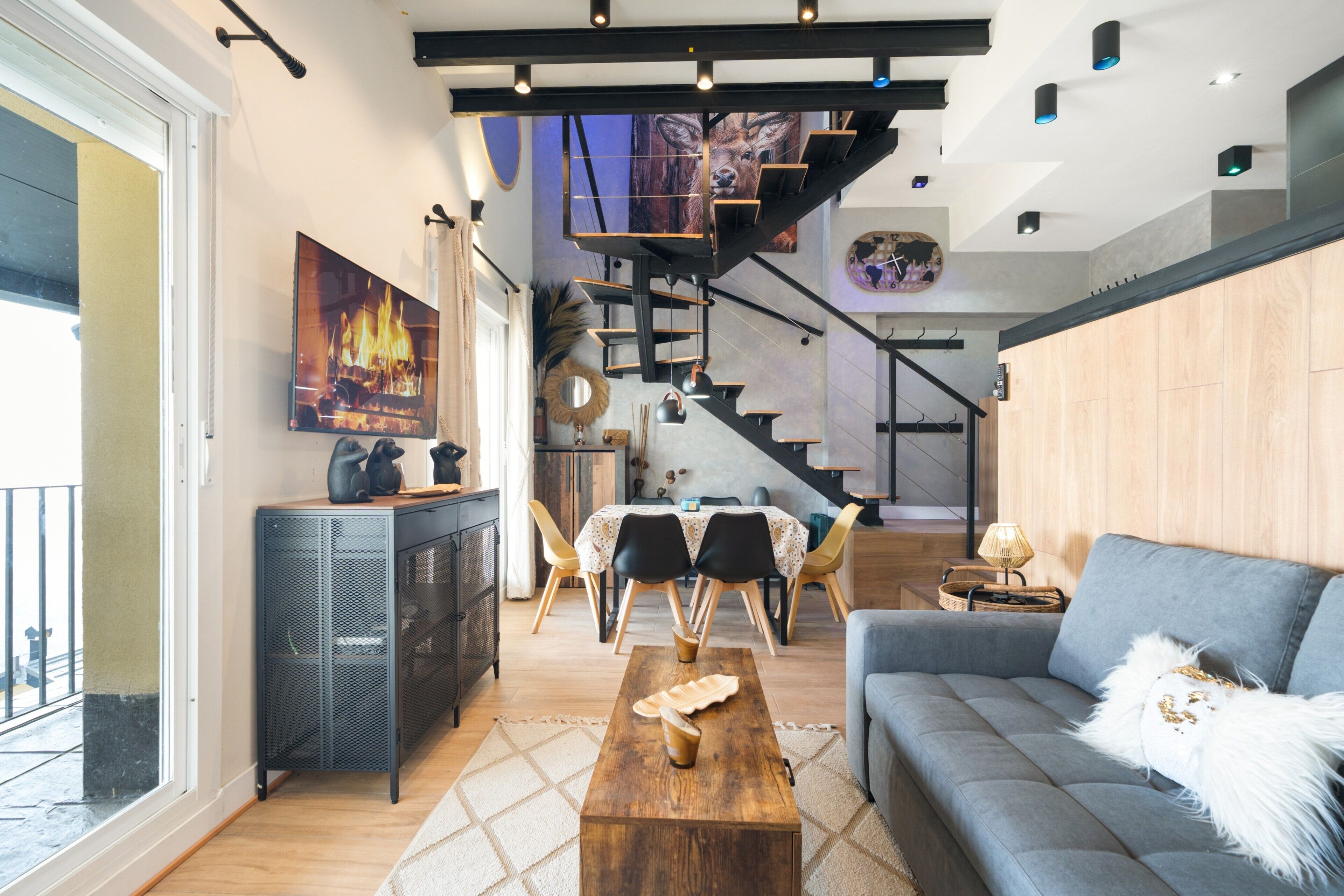A modern living room with a staircase, a dining area, and a large window.