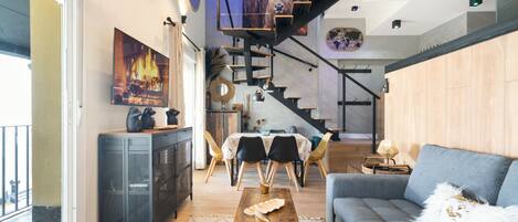 A modern living room with a staircase, a dining area, and a large window.