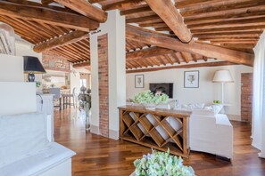 A spacious loft with exposed wooden beams, a dining area, and a living room with a sofa and a coffee table. - Casa Battisti in Lucca (Lucca)