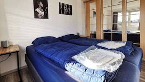 Et værelse med en stor seng, et lille bord og et skab med skydelåger.