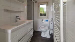 Et badeværelse med en hvid vask, toilet og et vindue.