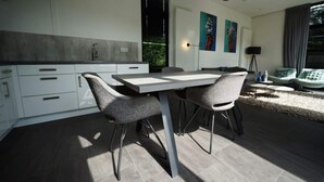 A modern kitchen with a dining area, featuring a large table and chairs, a built-in oven, and a view of the outdoors. - Holiday Home in Halfweg With Terrace (Halfweg)