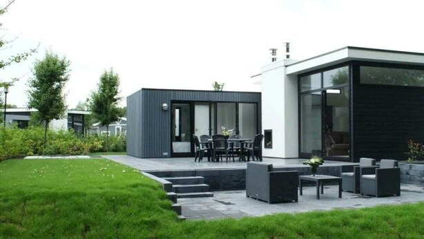 A modern house with a patio, outdoor seating, and a well-maintained lawn. - Holiday Home in Halfweg With Terrace (Halfweg)