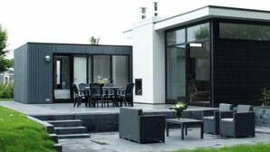 A modern house with a patio area, outdoor furniture, and a small garden. - Holiday Home in Halfweg With Terrace (Halfweg)