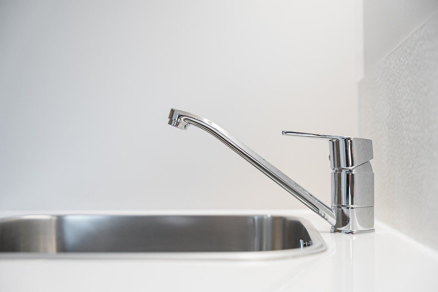 Ein modernes Küchenspülbecken mit chromfarbenem Wasserhahn und Einhebelmischer.