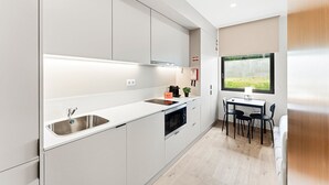 Una cocina moderna con armarios blancos, electrodomésticos de acero inoxidable y ventana con vistas a un jardín.