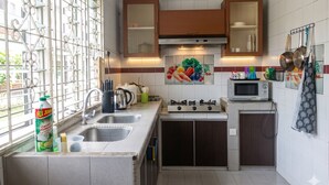 A kitchen with a gas stove, microwave, and a window with decorative metal grilles.