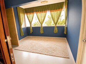 A room with a large window, a beige carpet, and a wooden door.