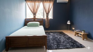 A bedroom with a bed, a window with curtains, a bedside lamp, a small wooden bench, and a rug.