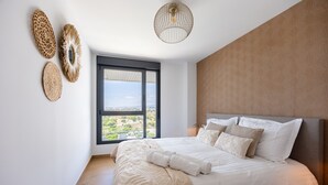 Quarto com uma cama grande, vista pela janela e luminária no teto.