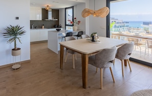 A modern kitchen with white cabinets, a dining area with a table and chairs, and a view of the ocean. - Allonbay Aster 6 - Sea View & Private Jacuzzi (Villajoyosa)